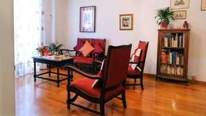 A living room with a wooden floor, a sofa set, a coffee table, and a bookshelf. - Happy place at the foot of Acropolis. (Athens)