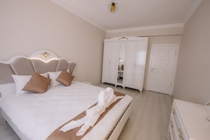 A bedroom with a large bed, a wardrobe, and a dresser.