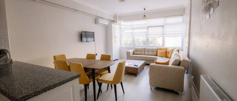 A modern living room with a sofa and a dining area with a table and chairs.