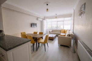 A modern living room with a sofa and a dining area with a table and chairs.