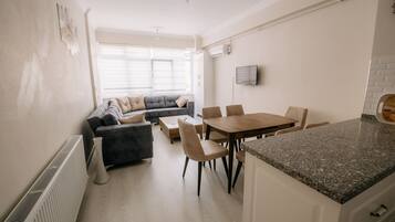 A modern kitchen with a dining area, a built-in oven, and a large window providing natural light.