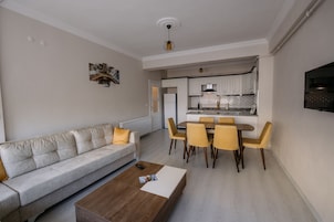 A modern living room with a sofa, coffee table, and dining area with chairs.