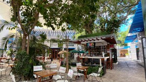 Un café en plein air avec des tables et des chaises, un Starbucks et un bar-restaurant proposant des collations, appelé Jem Bar & Snacks.