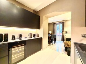 Una cocina moderna con armarios oscuros, horno empotrado y comedor con mesa y sillas.
