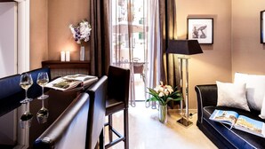 Una habitación de hotel moderna con comedor, sofá, lámpara de pie y vistas de la ciudad a través de amplias ventanas.
