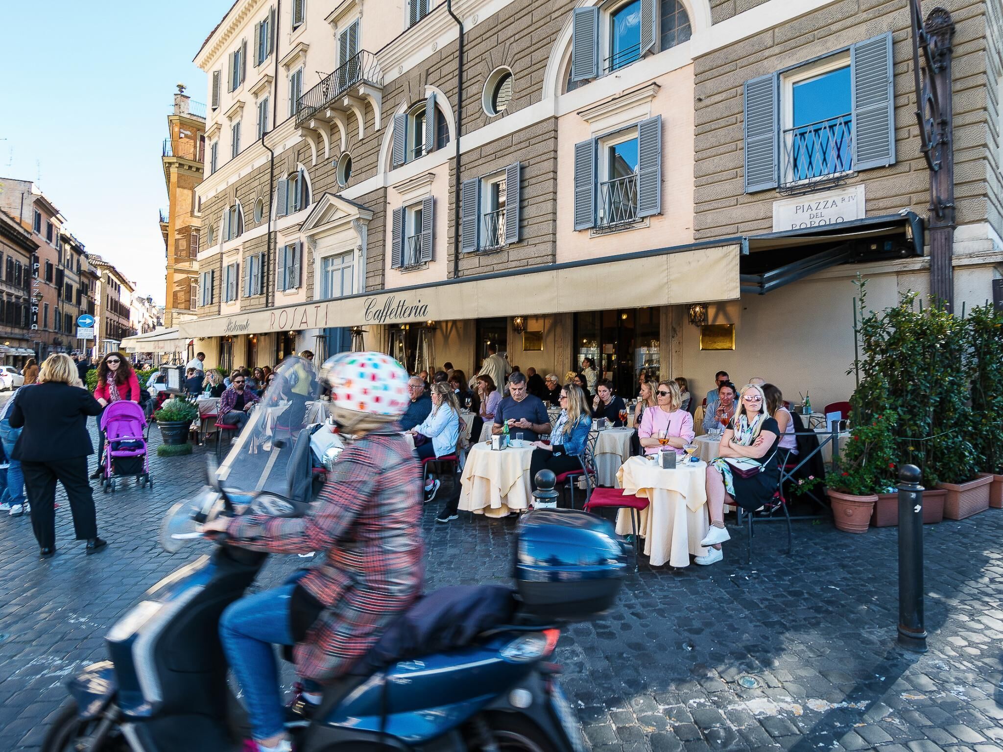 A bustling street scene with outdoor seating at a café.