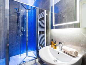 Une salle de bain moderne avec une douche à parois de verre, un lavabo blanc et une serviette.