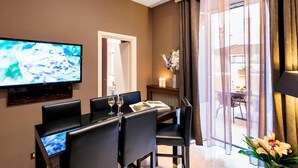 Habitación de hotel moderna con zona de comedor, televisor de pantalla plana y vistas al exterior.
