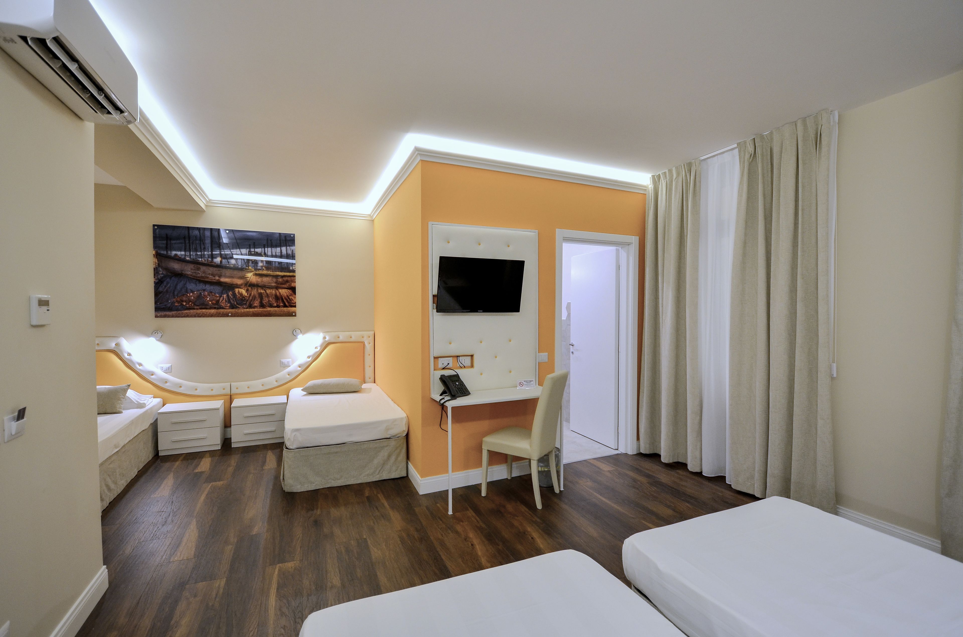 Une chambre d’hôtel avec un lit, un bureau, une chaise, une télévision et un tableau au mur.