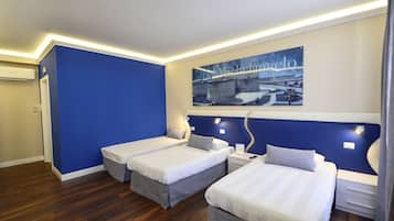 Ett hotellrum med två sängar, en blå accentvägg, en stor affisch med en bro på och ett trägolv.