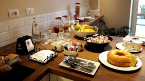 Un bufé de desayuno con diversas opciones de comida, una máquina de café y un cartel en un idioma extranjero.