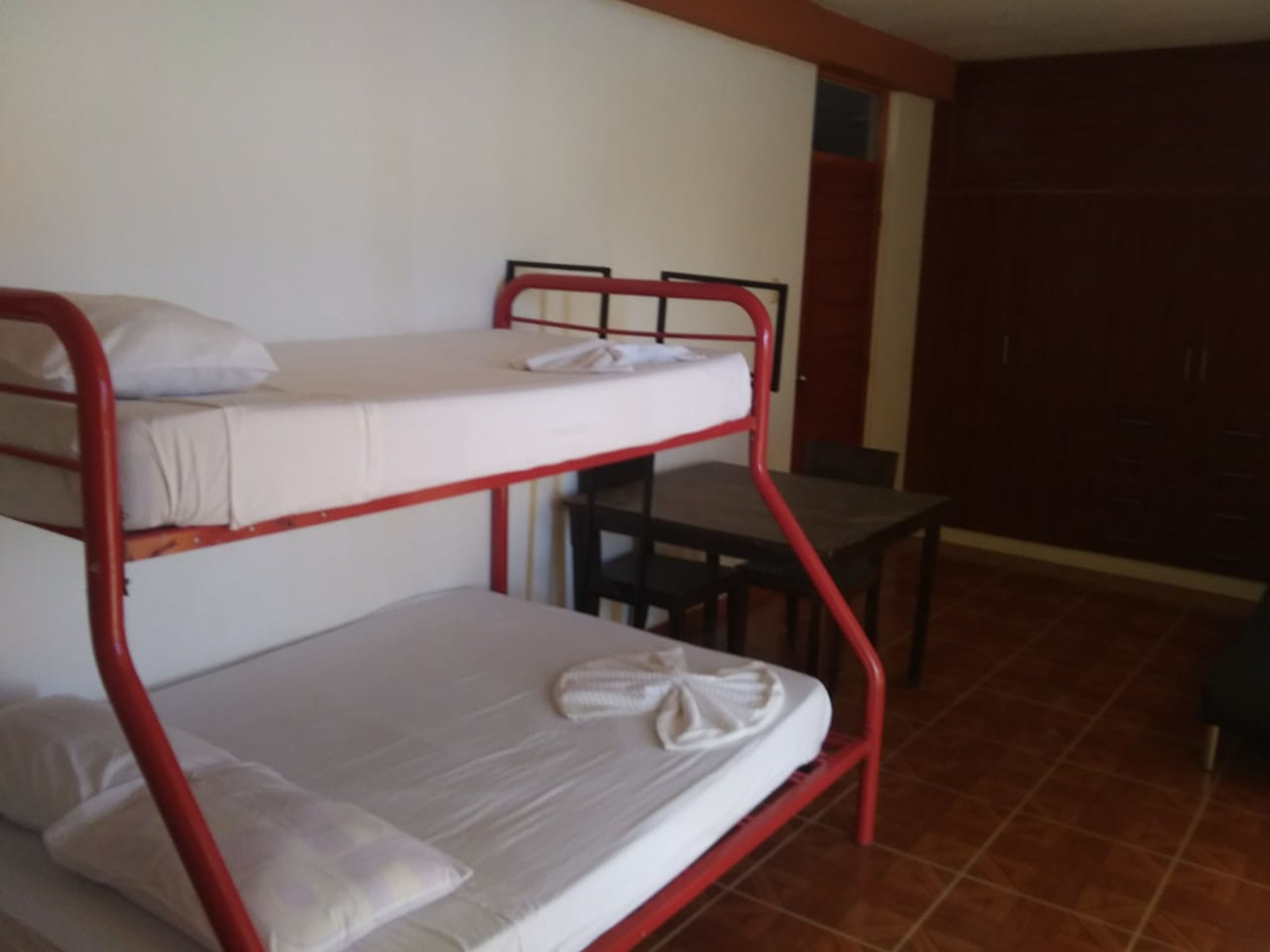 Een slaapkamer met een stapelbed, bureau en garderobe.