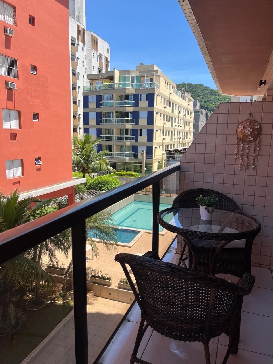 A balcony with a view of a swimming pool, a red building, and a multi-story complex.