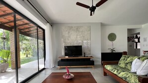 A modern living room with a TV, sofa, and dining table. - Guaeca, the paradise of the North Coast. (São Paulo)