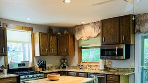 Una cucina con armadietti in legno, un'isola centrale, un piano cottura, un forno a microonde e una lavastoviglie.
