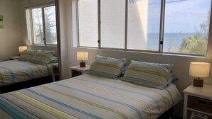 A hotel room with two beds, each with striped bedding and bedside lamps.