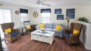 A living room with wicker furniture, a white coffee table, nautical decor, and a ceiling fan. - Remodeled 4 BR Waterfront Beach House with all the Comforts of Home...and more! (Clinton)