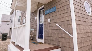 A two-story building with a porch, a blue door, and a sign that reads 'Summer Cottage.' - Remodeled 4 BR Waterfront Beach House with all the Comforts of Home...and more! (Clinton)