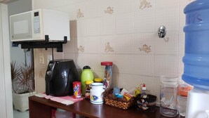 Un plan de travail de cuisine équipé d’un four à micro-ondes, d’une machine à café, d’un distributeur d’eau et de divers ustensiles de cuisine.