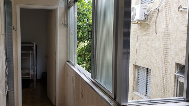 Un couloir étroit avec une fenêtre, une porte et un radiateur.