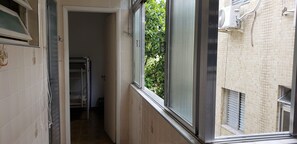 A narrow hallway with a window, a door, and a radiator. - Apartamento Enseada - Ed. Mabe (Balneario Guarujá)