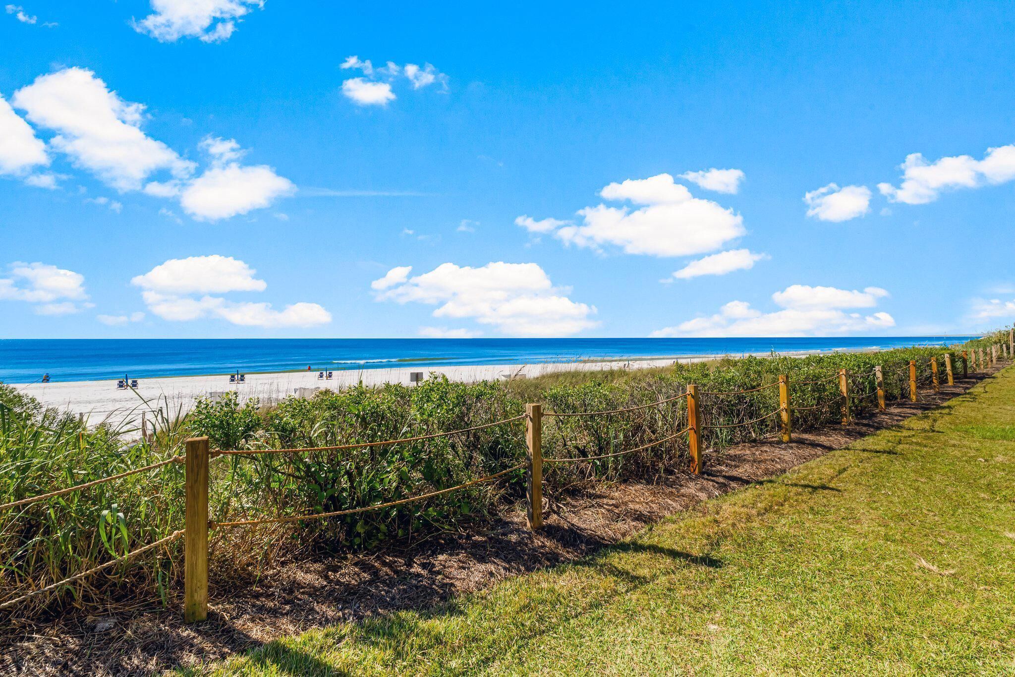 A beach with a wooden fence and a grassy area.