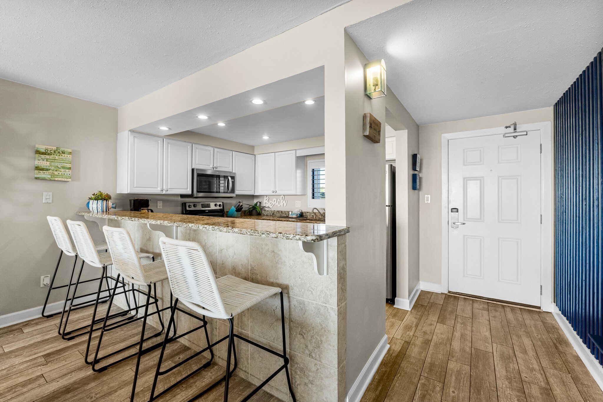 A modern kitchen with white cabinets, a granite countertop, and a built-in island with bar stools.