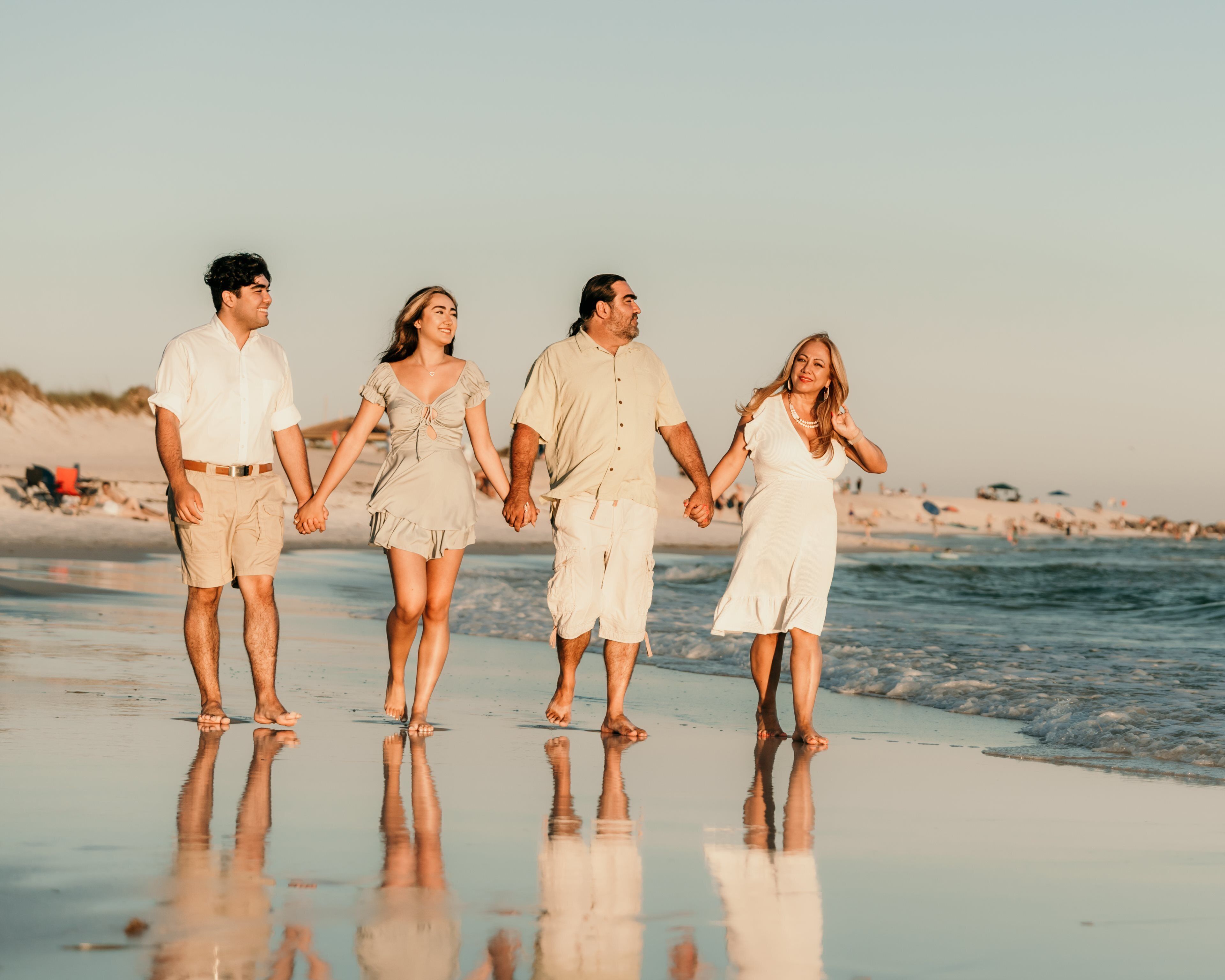 A family walking on a beach with a clear sky.
