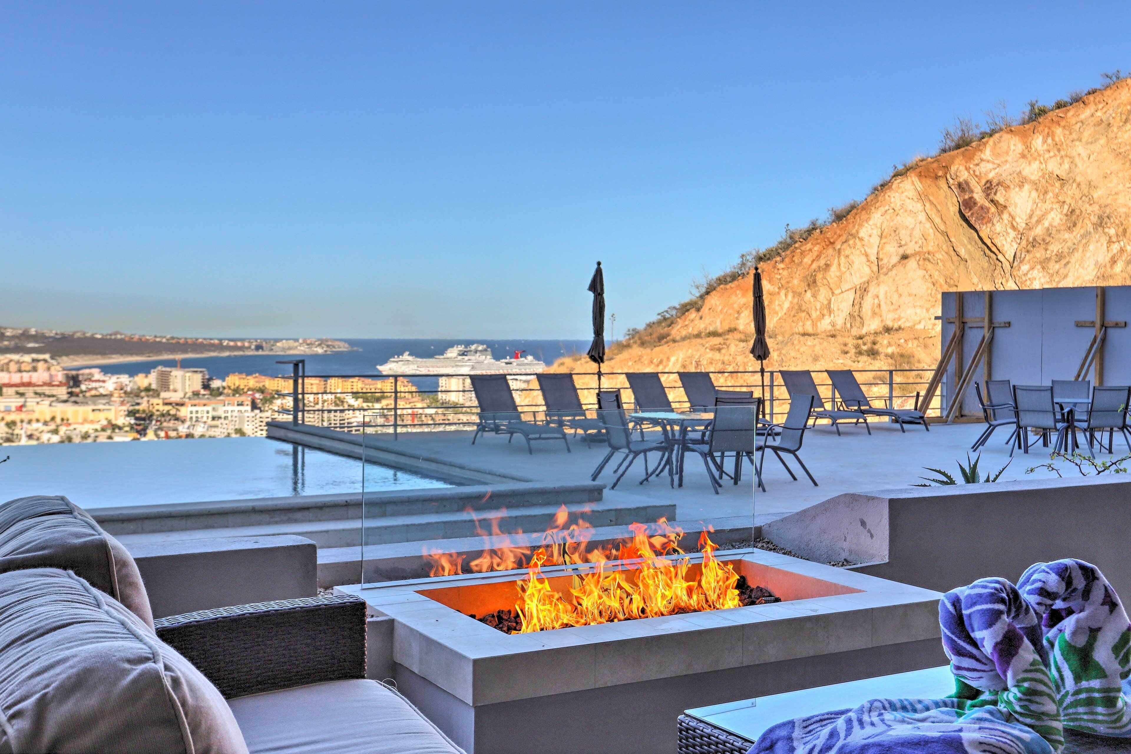 Terraza en la azotea con un hogar para fuego, sillones de descanso y vistas a la ciudad y al mar.