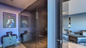 A modern bedroom with a large wardrobe, a bed, and a painting on the wall.