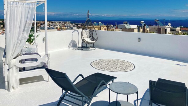 A rooftop terrace with a bed, a hanging chair, and a table. - Traditional Villa Sofia - a Greek village dream!! (Koskinou)