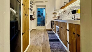 A narrow kitchen with wooden cabinets, a chandelier, and a view into the dining area. - Traditional Villa Sofia - a Greek village dream!! (Koskinou)