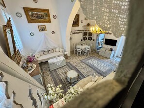 A spacious living area with a high ceiling, a dining table, a sofa, and a TV.