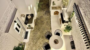 A spacious courtyard with a seating area, a round table, and potted plants. - Traditional Villa Sofia - a Greek village dream!! (Koskinou)