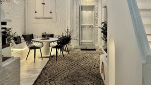 A white-walled room with a round table and chairs, a door, and a staircase. - Traditional Villa Sofia - a Greek village dream!! (Koskinou)