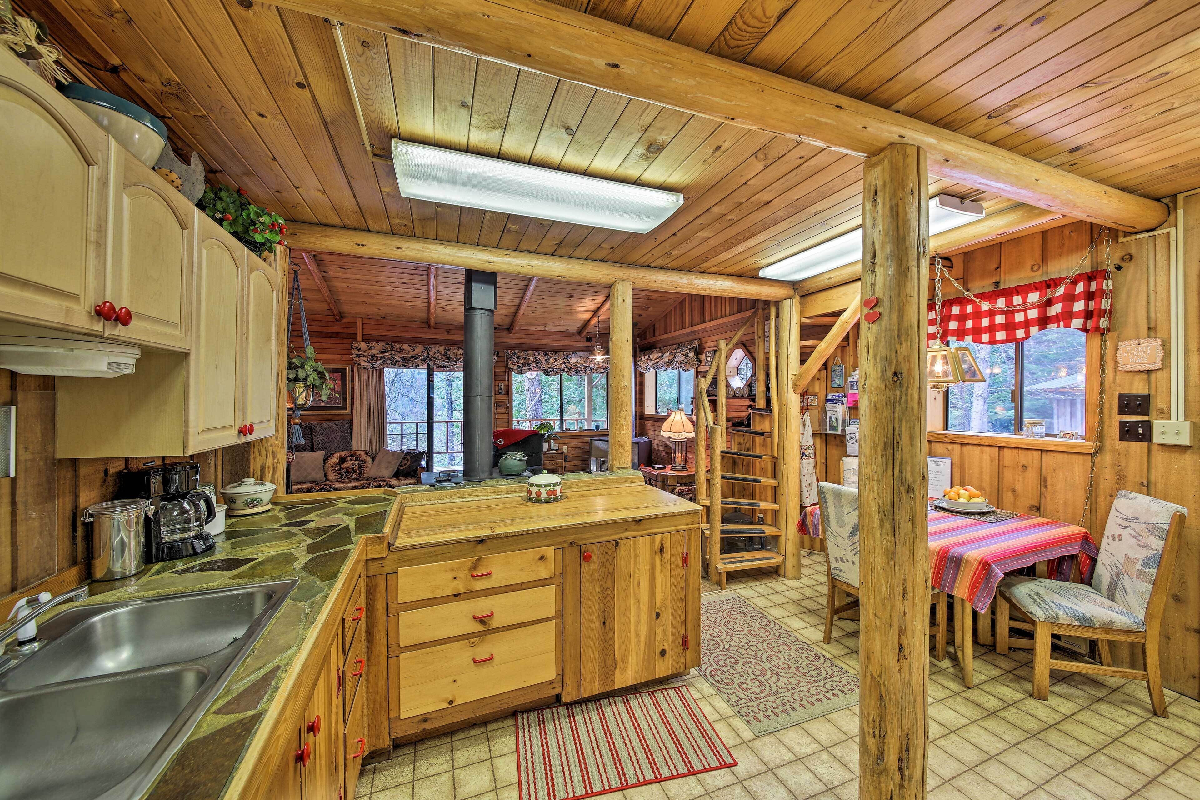 Een rustiek houten interieur met een keukenhoek, eettafel en een gezellige open haard.