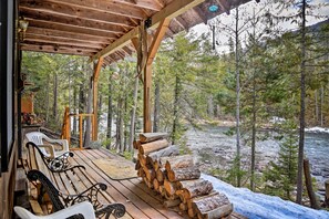 Una terraza de madera con un banco y un cartel de bienvenida, con vista a un río y un bosque.