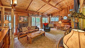L’intérieur d’un chalet confortable, avec un plafond en bois, un ensemble de canapés, une table basse et une cheminée.