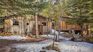 Une cabane rustique avec une façade en bois, une terrasse et une pile de bois de chauffage à proximité.