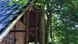 A rustic wooden structure with a stone wall and a metal roof, surrounded by trees.