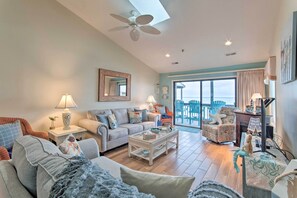 A spacious living room with a large sofa, a coffee table, and a dining area with chairs. - Topsail Beach Oceanfront Oasis w/ Stunning Views! (North Topsail Beach)