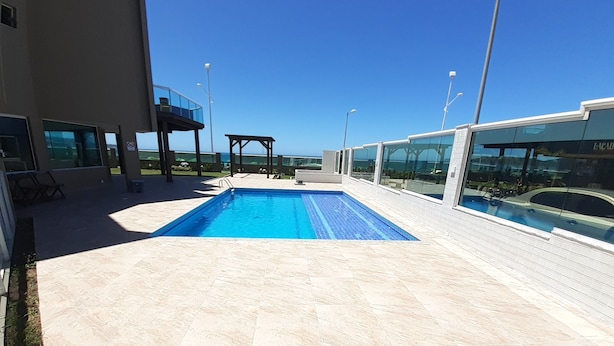 Une piscine sur le toit, avec une eau d’un bleu cristallin, entourée d’une terrasse carrelée et bordée d’une architecture moderne.