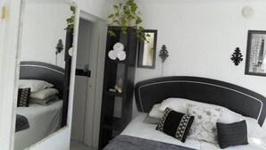 Un dormitorio con cama, espejo, ventilador de techo y una planta.