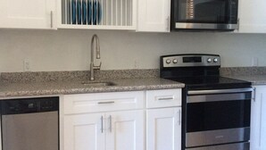 A kitchen with white cabinets, a stainless steel stove, a microwave, and a dishwasher.