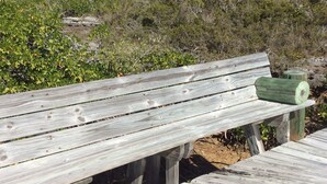 A wooden bench on a wooden deck with a natural landscape in the background.