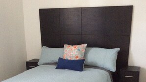 A bed with a quilted cover, two pillows, and a headboard.