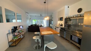 Una cucina moderna con isola in legno, elettrodomestici in acciaio inossidabile e un'area pranzo con sgabelli da bar.