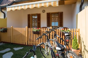 Home sweet home, where a bicycle waits by the picket fence, surrounded by lush greenery and a charming porch.