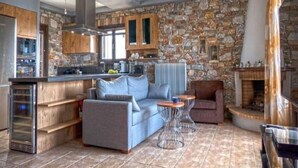Une cuisine moderne avec des murs en pierre, un four encastré et un coin salon comprenant un canapé et une table basse.