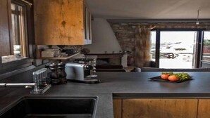 Une cuisine moderne avec un mur d’accent en pierre, un grand meuble en bois et une vue sur l’extérieur grâce à une grande fenêtre.